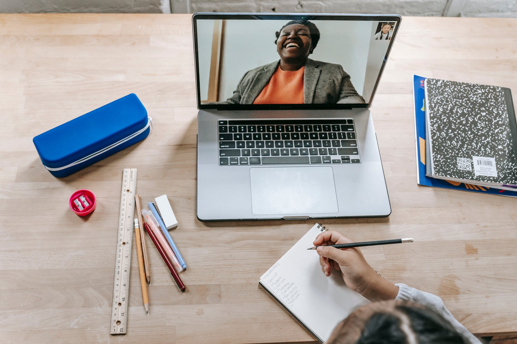 Smart girl writing lecture of teacher speaking online